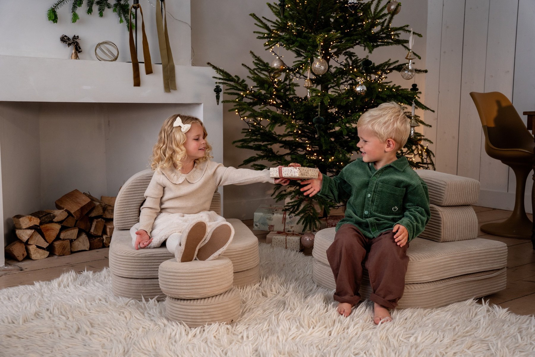 Zwei Kinder schenken sich ein Geschenk am Weihnachtsbaum