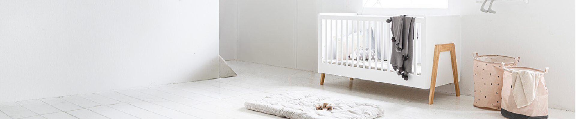 Babyzimmer mit weißem Babybett und Spielmatte